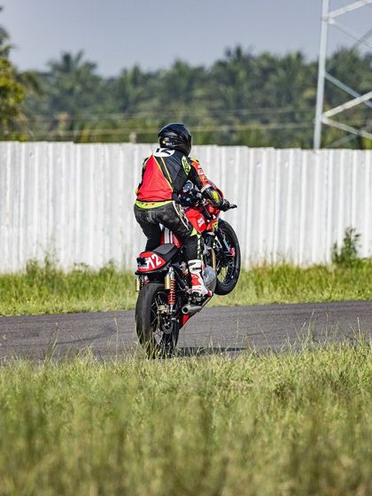 A controlled wheelie executed on a race-prepared Royal Enfield GT on a professional track. This showcases the fundamental stunting skills that form the basis of our more complex event choreography.
