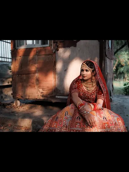 A wide-angle portrait of the bride seated in a rustic, outdoor setting. The dramatic lighting and composition create a powerful and artistic image.