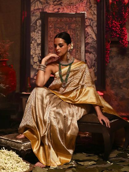A regal seated pose from the Soho Begum campaign, showcasing the grandeur of the golden silk saree.