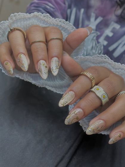 This design combines a glittery cat-eye base with delicate, hand-painted gold chrome vines. It's a perfect example of mixing different effects for a rich, detailed look.