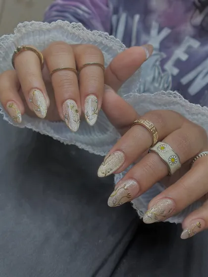 This design combines a glittery cat-eye base with delicate, hand-painted gold chrome vines. It's a perfect example of mixing different effects for a rich, detailed look.