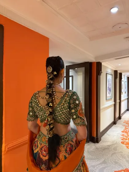 The bride walking down a hallway, showing how a long, traditional braid moves and complements the entire bridal ensemble. The hairstyle is both a statement piece and a functional part of the look.
