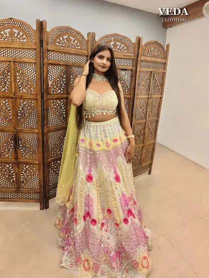 The combination of yellow, pink, and mirror work makes this lehenga incredibly festive and joyful.