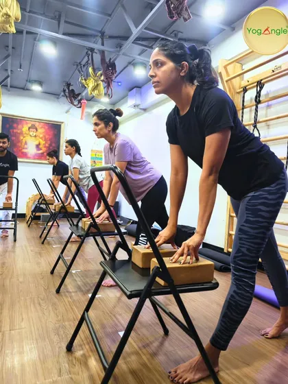 A glimpse into one of our Foundation Workshops. Here, students use chairs and blocks to learn proper alignment in a standing pose. This group setting fosters focus and shared energy, with instructors providing guidance to ensure everyone finds stability and strength.