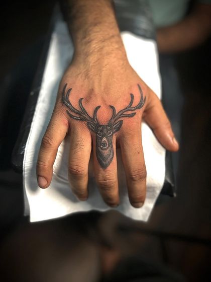 Another angle of the deer finger tattoo, showing how it fits perfectly on the middle finger. It's a great example of small, detailed work.