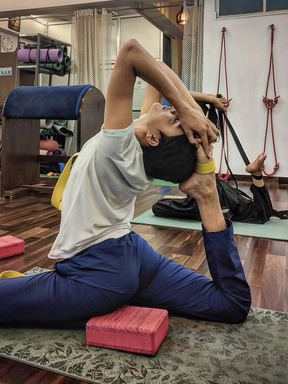 A student practices a deep hip-opening asana, using a block for support to ensure correct alignment.