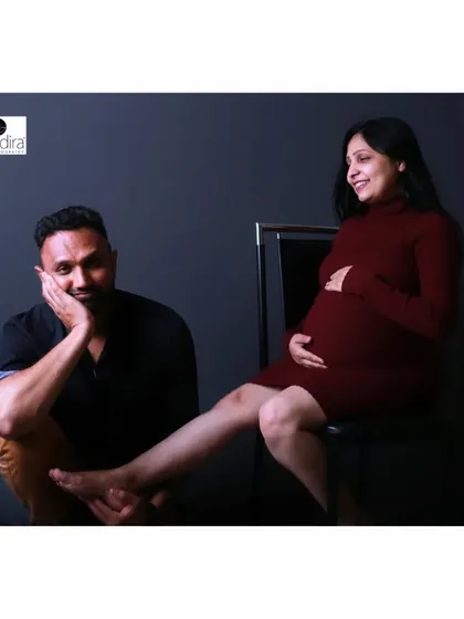 A playful and caring moment captured in the studio, with the father-to-be pampering his partner by holding her foot.