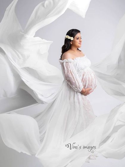 Angelic and pure. This portrait in a flowing white lace gown creates a soft, ethereal look. The fabric seems to float around her, giving the image a dreamy quality.