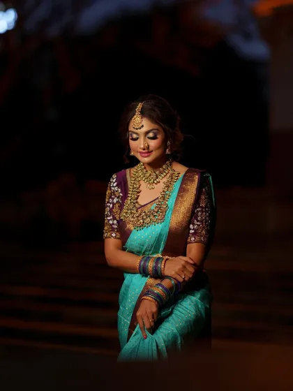A dramatic shot of a model in a beautiful silk saree, adorned with our heavy temple jewellery set. The lighting highlights the rich texture and matt gold finish of the pieces.