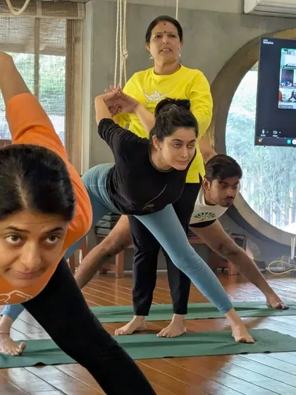 A student receives a hands on adjustment in Parsvottanasana (Pyramid Pose). This kind of support helps build strength and balance, especially for beginners.