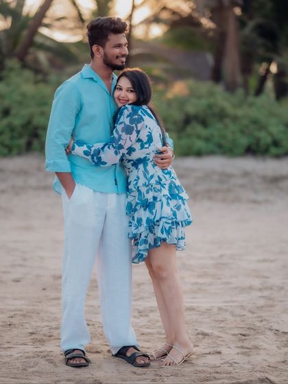 A sweet and simple hug on the beach. The bride-to-be wraps her arms around her partner, smiling at the camera, capturing a moment of comfort and happiness.