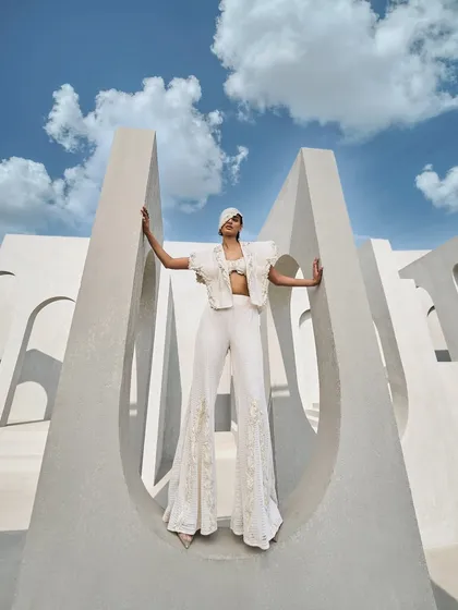 The ivory mesh pantsuit, paired with a structured bustier, balances strength and sensuality in perfect harmony.
