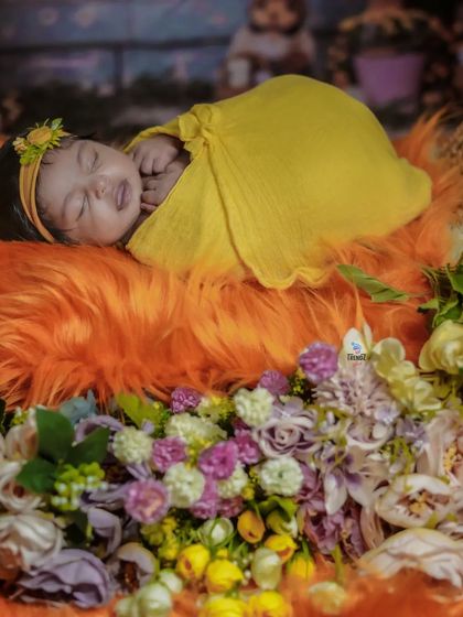 A newborn smiling in their sleep, surrounded by a wreath of colorful flowers. A truly magical moment.