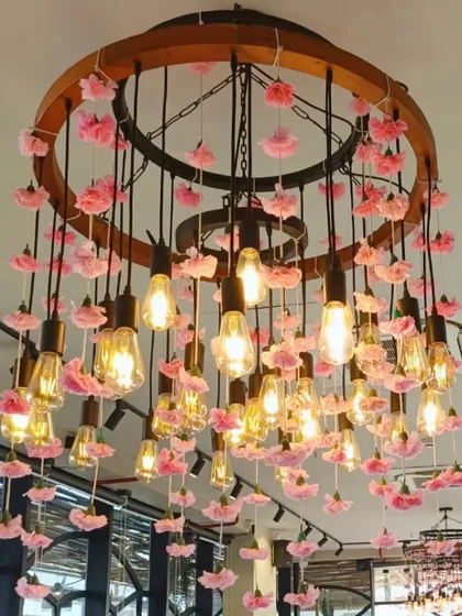 A custom chandelier made of hanging Edison bulbs, each adorned with a delicate pink flower.