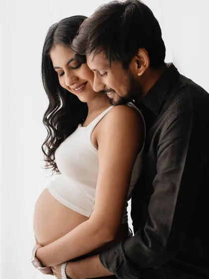 A tender moment between the couple. This close-up shot in their casual outfits feels so intimate and real. The soft lighting highlights their connection and the beautiful baby bump.