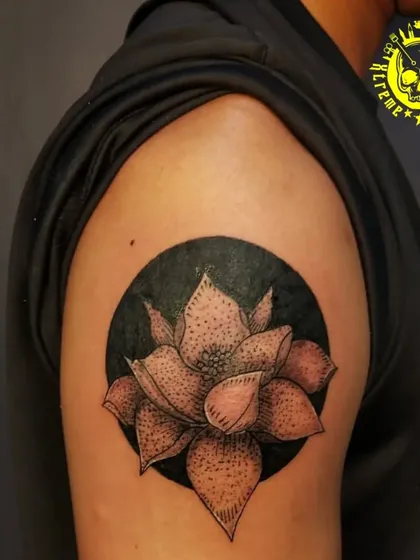 A dotwork style lotus flower against a solid black circle. This technique, called stippling, uses tiny dots to create shading and texture, giving the tattoo a unique look.