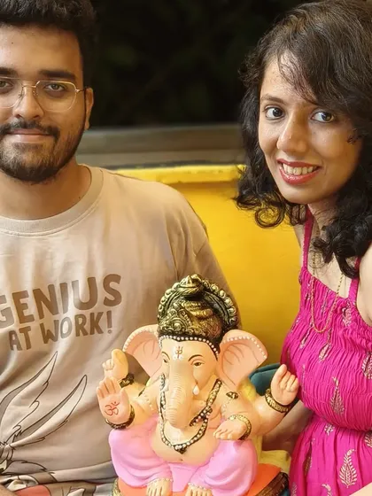 A couple proudly displays the Ganpati idol they painted together at our workshop. It's a wonderful activity for friends and family to share a creative experience.