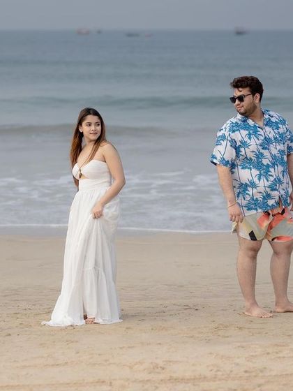 A candid and relaxed shot of the couple on a serene Goan beach, capturing a natural moment from their pre-wedding shoot.
