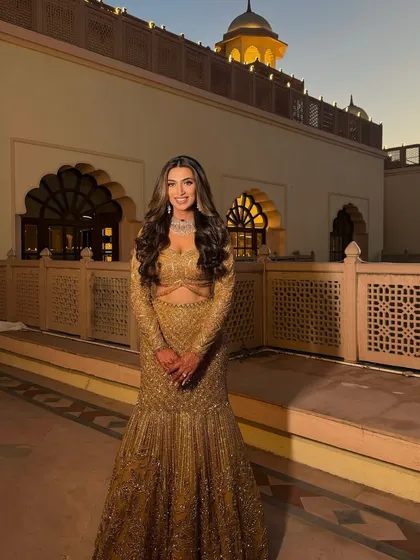 A full-length view of the golden sangeet look. The entire ensemble is fit for a queen, with makeup that is both radiant and regal.