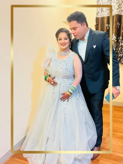 A reception look that is both glamorous and elegant. The groom wears a classic dark suit, allowing his partner's shimmering silver gown to take center stage.