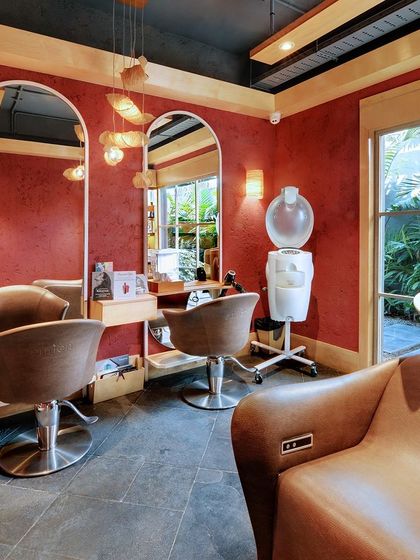 Even the more private rooms at Enrich Salon, like this hair wash area, feature large windows with views of the garden. The rich red walls create a warm, intimate contrast to the vibrant green outside.