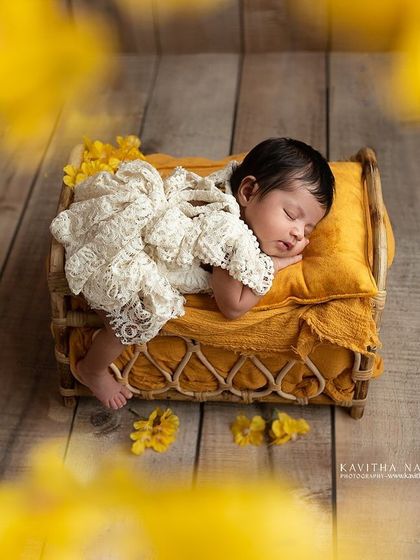 A newborn sleeps peacefully on a tiny bed with a yellow blanket, surrounded by a dreamy haze of yellow flowers. This artistic shot is full of warmth and happiness.