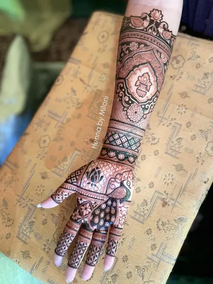 A beautiful bridal mehendi with a peacock on the palm and a kalash motif on the wrist. The design extends up the arm with classic patterns.