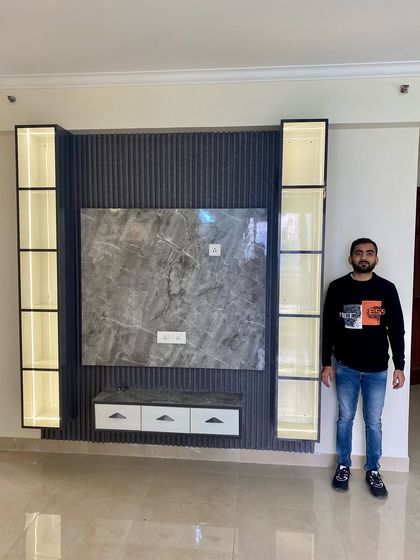Another completed TV unit, featuring a grey marble back panel, dark fluted details, and floating display cabinets with internal lighting.