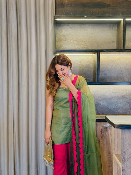 A candid moment showing the beautiful drape of the organza dupatta. The lightweight fabric adds grace and movement, while the color contrast creates a memorable look.