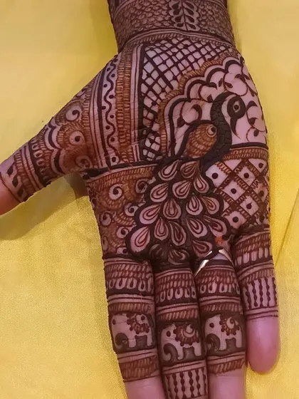 A detailed close-up of a peacock on the palm, with tiny elephants decorating the fingertips.