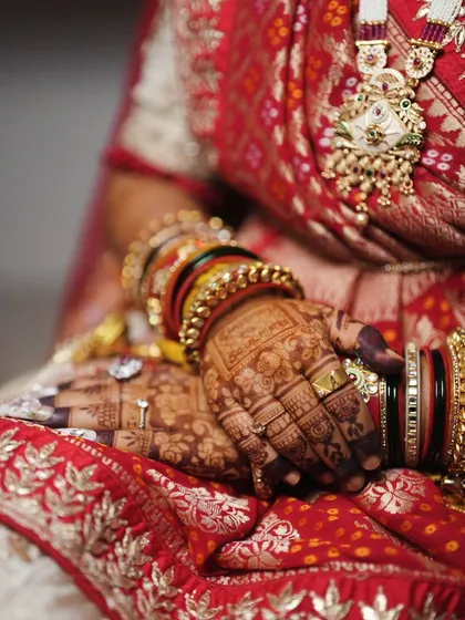 Another angle of the bride's hands, highlighting the rich detail of her jewelry and the way the mehendi enhances her overall bridal attire.