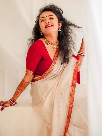 A bright, happy bridal portrait against a simple white curtain. The bride's natural smile and flowing hair give this shot an effortless charm.