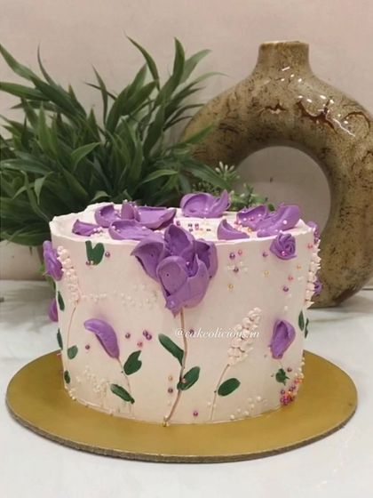 There is something so beautiful about hand-piped florals. This cake features delicate purple flowers piped directly onto the buttercream, creating an artistic and textured design.