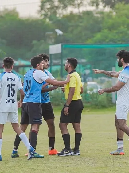 Tensions can run high during a match, but sportsmanship is always key. Players and referees in discussion.