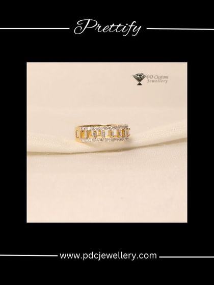 A prettifying diamond band in 18kt hallmarked gold. The design features baguette-cut diamonds channel-set between rows of round brilliant diamonds for a modern, geometric look.