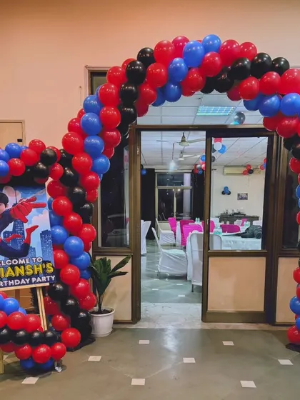 A heart-shaped balloon arch in Spiderman's signature red, blue, and black colors, creating a fun entrance for the birthday party.