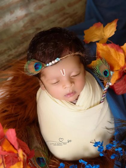 Wrapped in cream and surrounded by autumn leaves and peacock feathers, this little Kanha looks so peaceful. The combination of colors and textures creates a unique and artistic portrait.