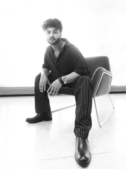 A sharp, monochromatic look for the 'Kota Factory' promotions. The black shirt paired with pinstripe trousers and Chelsea boots creates a sleek and stylish ensemble.