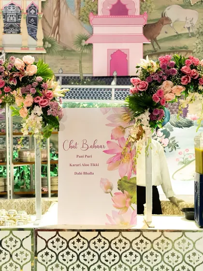 A "Chaat Bahaar" counter elegantly decorated with fresh flowers and a beautifully designed menu. This setup elevates a simple chaat station into a sophisticated culinary highlight.