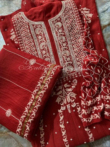 A flat-lay presentation of the complete Sindoori Red Anarkali set. This view shows the coordination between the kurta, dupatta, and the detailed border work.