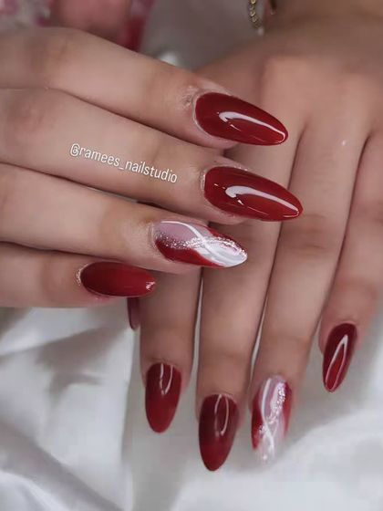 When in doubt, keep it classy. This beautiful set features long, almond-shaped nails in a classic deep red, with two accent nails that have a white and red marble design.