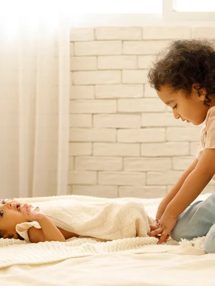 A gentle moment between sisters. The older sister looks on with such love and curiosity at the new baby, a precious memory for the whole family.