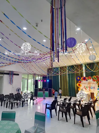 The full party space for the Art & Craft theme. The ceiling is decorated with colorful streamers and paper lanterns, creating a festive and creative atmosphere without using balloons.