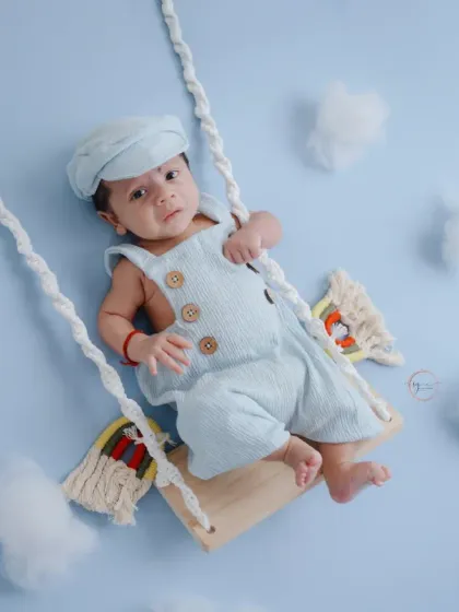 This little one looks so peaceful and content on his cloud swing, creating a serene and imaginative newborn portrait.