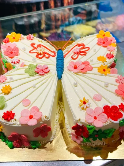 A unique cake sculpted into the shape of a butterfly, with wings decorated with colorful flowers.