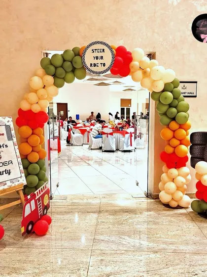 The entrance to the 'Cars' party, featuring a balloon arch in theme colors, a personalized welcome sign, and fun props like a stack of tires.
