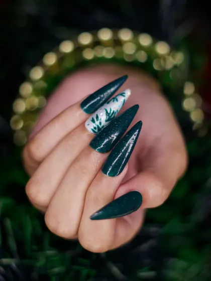 This image captures the subtle shimmer in the dark green polish. The hand-painted foliage on the accent nail stands out, demonstrating a more understated approach to festive nail art.