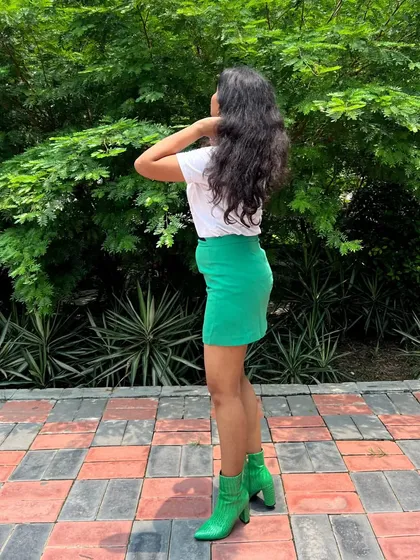 A side profile of the green-on-green outfit. The fitted skirt and heeled boots create a chic silhouette that's perfect for a day-to-night transition.