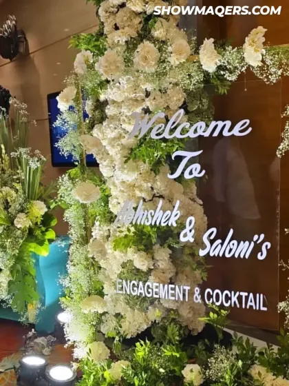 A close up of the welcome sign for the engagement, beautifully integrated into a wall of white flowers.