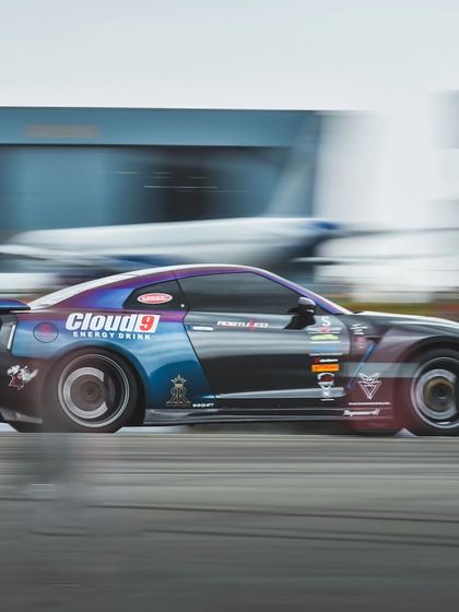The same Nissan GTR, a blur of motion against the backdrop of an airplane hangar. This unique venue adds a dramatic element to our event photography.